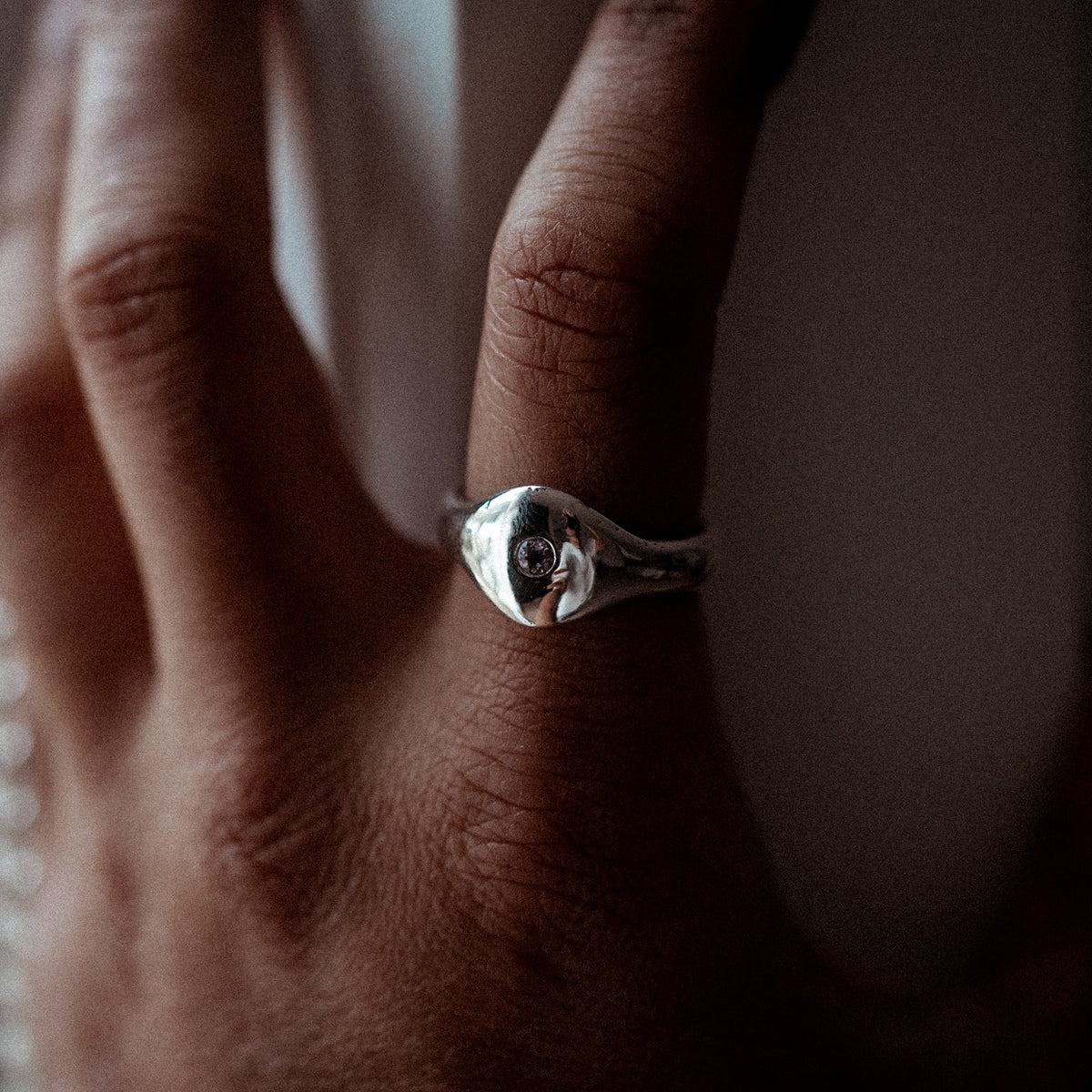 The Last Light amethyst signet ring worn on the hand